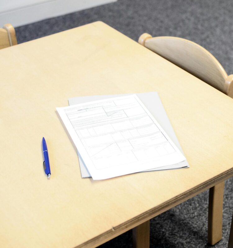 Empty classroom desk with paperwork and pen, ideal for educational themes.